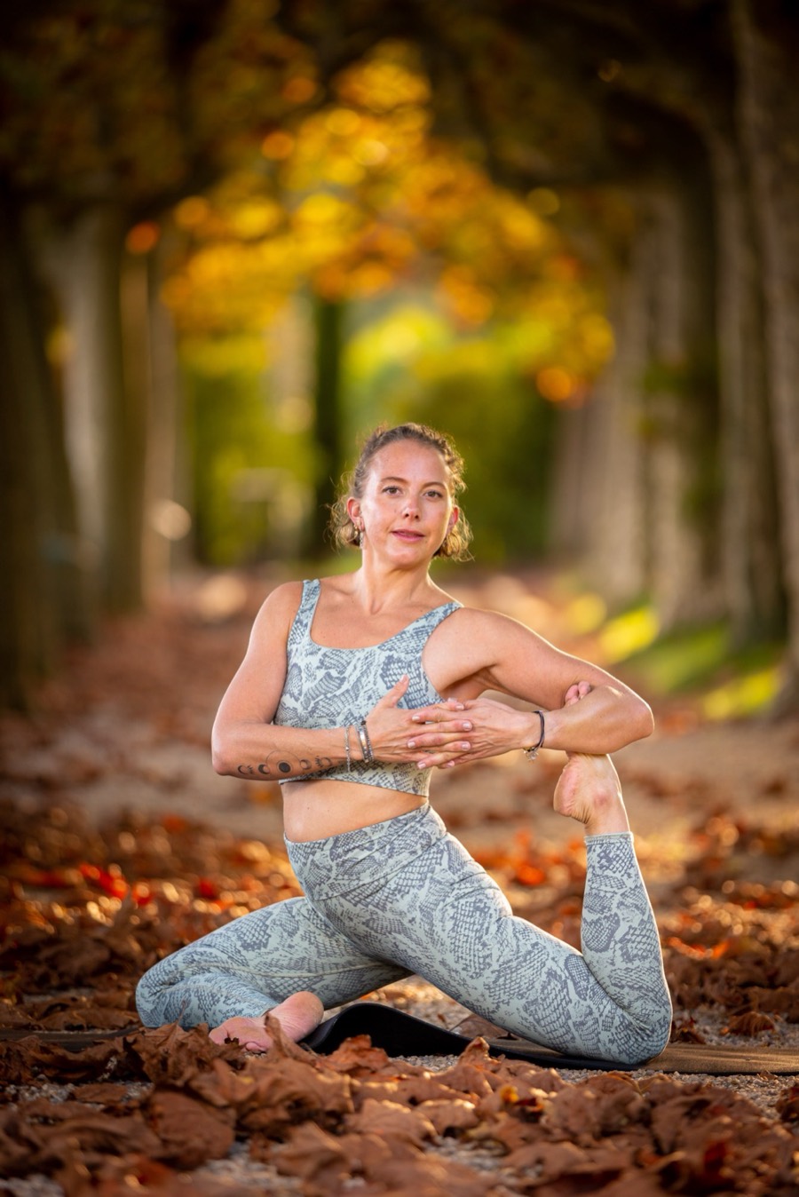 Sabine in a deep, controlled mobility pose among autumn trees